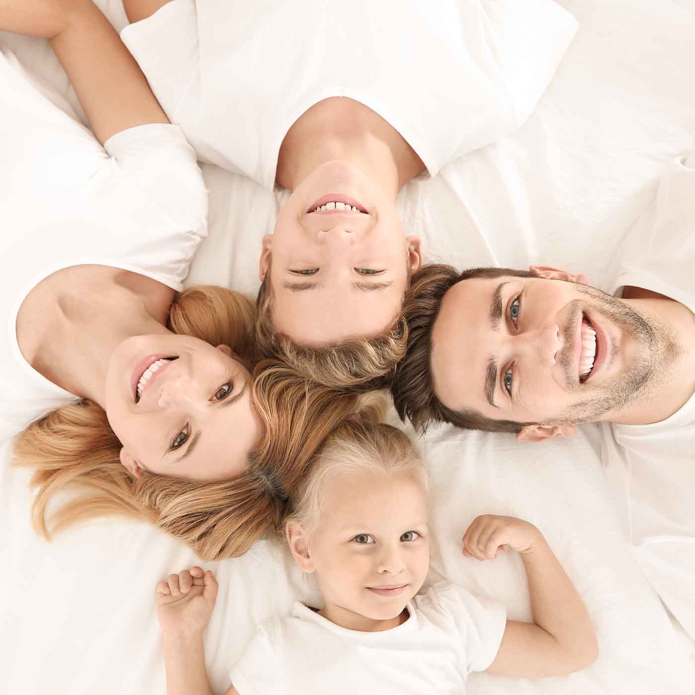 Papà, mamma, figlio e figlia. Famiglia sorridente sul proprio materasso by Beliamo